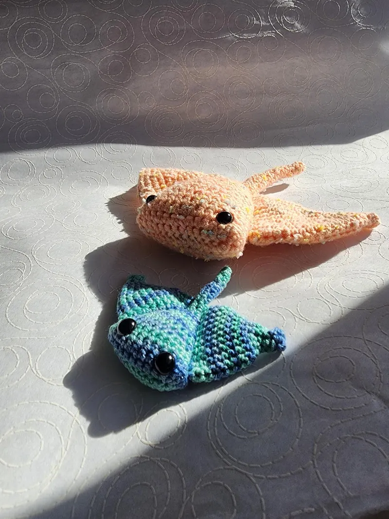 A pair of crochet stingrays; orange and blue.