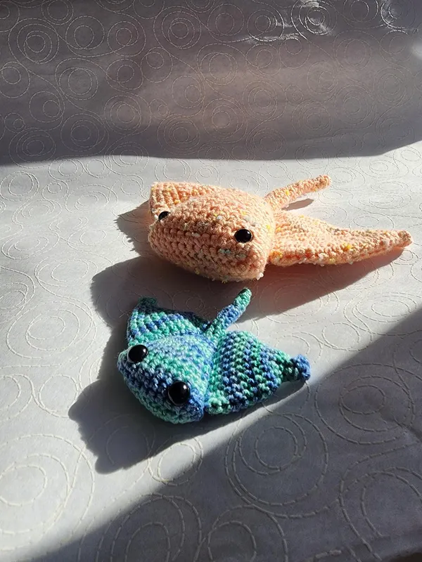A pair of crochet stingrays; orange and blue.